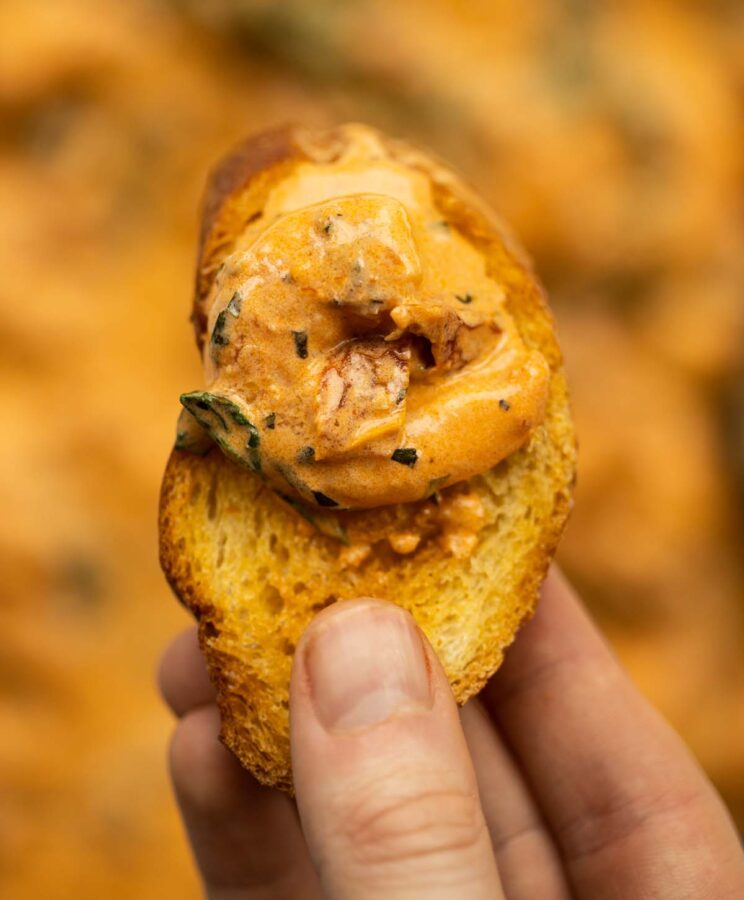 creamy Tuscan prawn close up overhead shot of hand holding bread with creamy Tuscan prawn on it