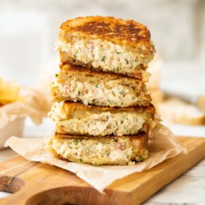 4 chicken melt halves stacked on each other on wooden board